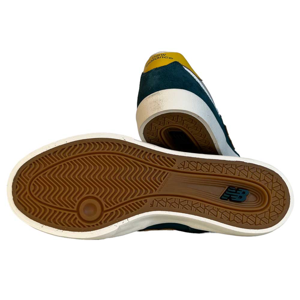 The 574 VOK New Balance Numeric Gray White Suede Shoes feature a gum-colored textured sole, a small Numeric logo, and heel accents in blue and yellow.