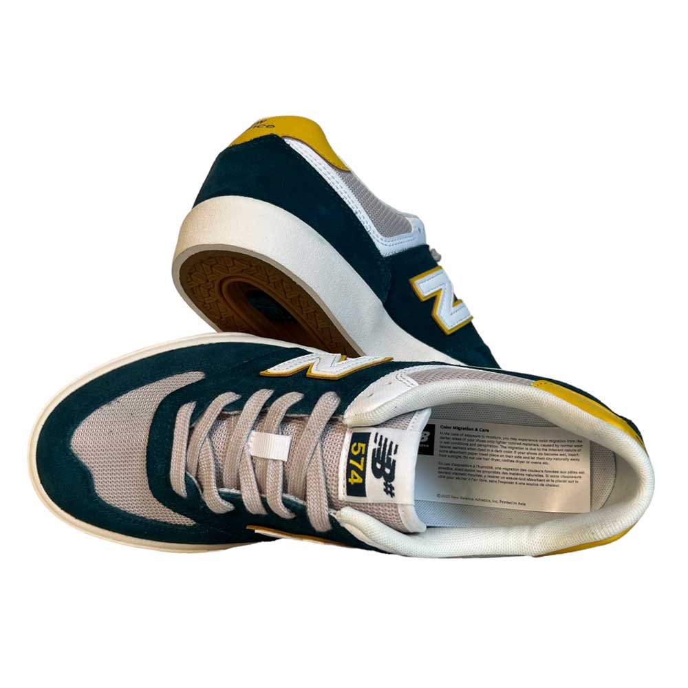 The 574 VOK New Balance Numeric Gray White Suede Shoes, shown in teal, gray, white, and yellow—one on its side and one upright—feature a classic design inspired by New Balance Numeric skate shoes.