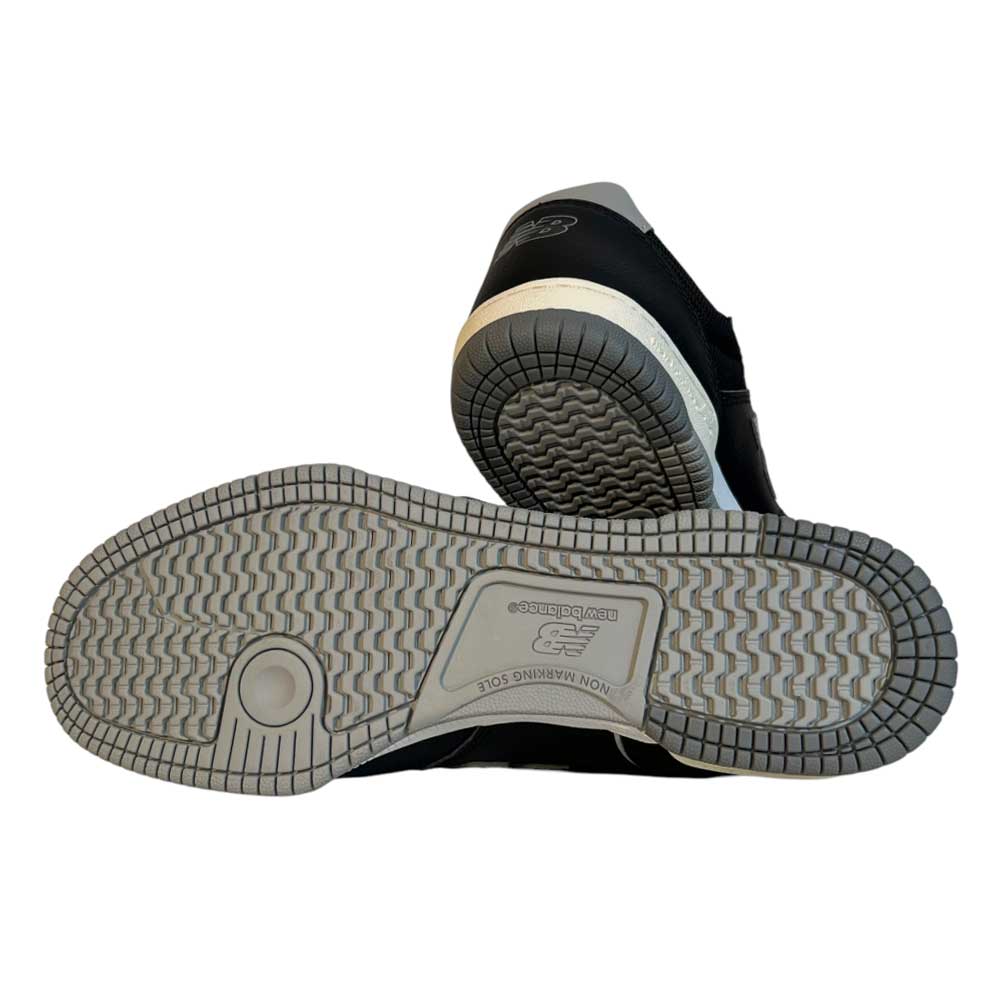 A pair of 6600 BBW Tom Knox New Balance Numeric Suede Shoes in black and white, with one shoe on its side highlighting the textured, light-gray rubber sole, circular tread pattern, and embossed branding.