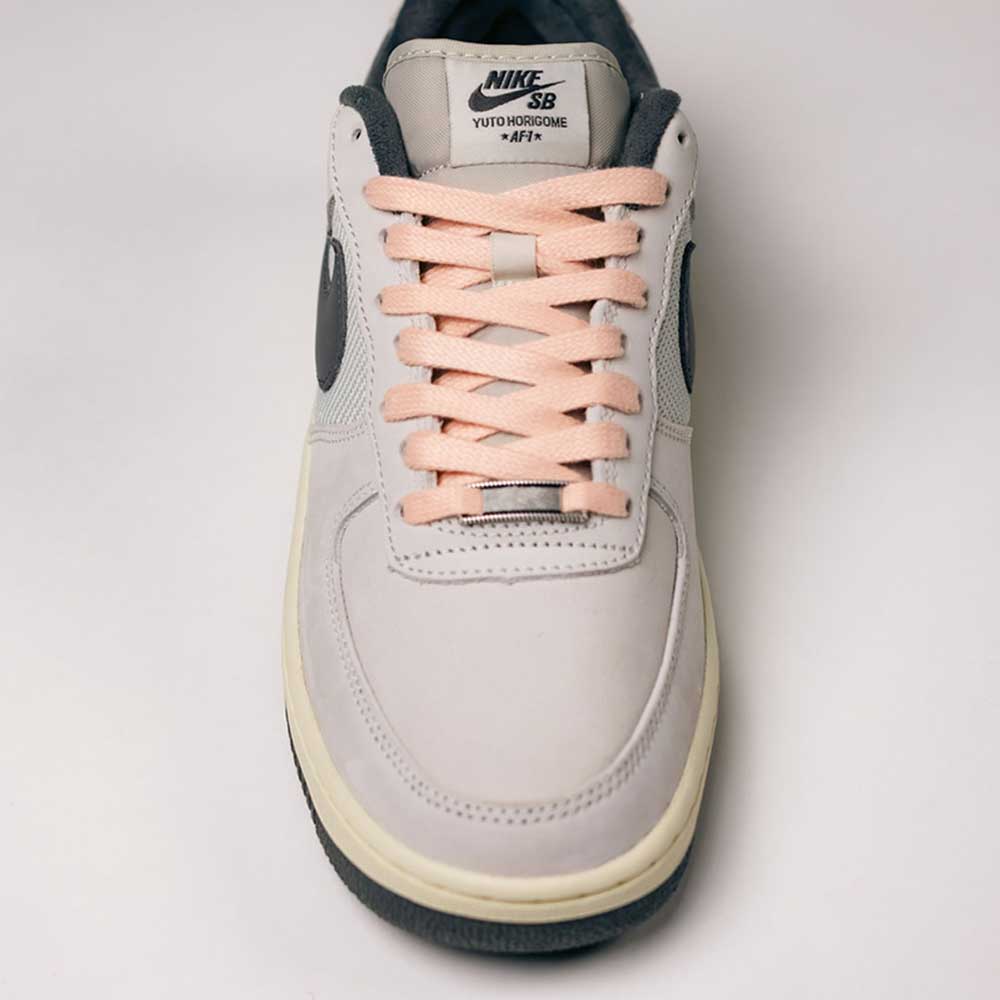 A pair of Yuto AF1 Iron Grey White Coconut Milk IO8439100 Nike SB Suede Skateboarding Shoes, featuring a light iron grey suede upper, peach laces, black accents, and “Yuto Horigome” text on the tongue—viewed from above against a plain background—blending iconic skate shoe design with signature Nike Air cushioning for lasting comfort.