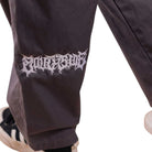 A close-up of a person wearing Texas Icon Gray Southside 94 Pants, featuring white stylized text on the leg, paired with black-and-white sneakers against a plain white background.