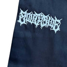 A close-up of Texas Icon Black Southside 94 Pants shows dark fabric with a white, graffiti-style embroidered logo. The jagged lettering, inspired by Southside skateboarding, gives the text an edgy, hard-to-read look.