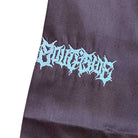 A close-up of black fabric with light blue graffiti-style "Futurism" text, stitched on loose-fitting Texas Icon Brown Southside 94 Pants inspired by skate style.