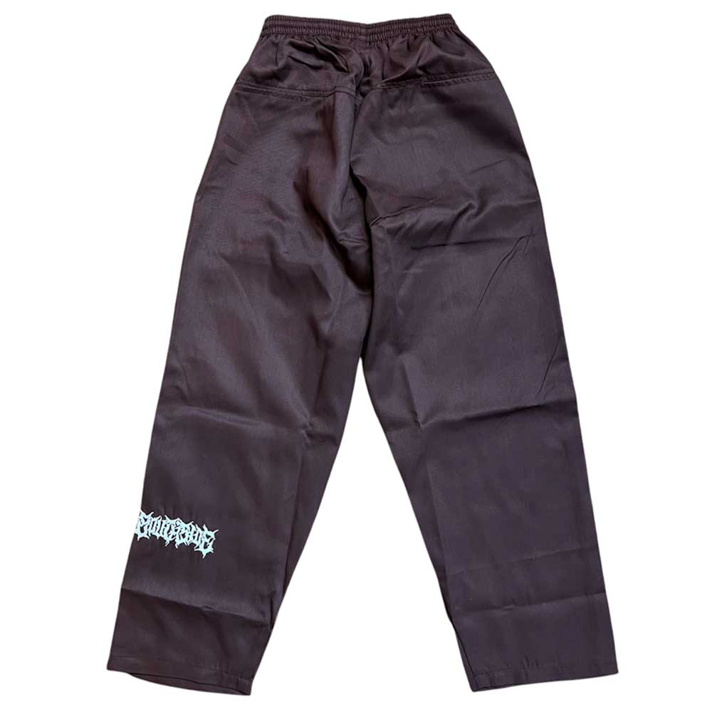 The Texas Icon Brown Southside 94 Pants feature an elastic waistband and a white graphic near the lower left leg—classic, loose-fitting skate pants perfect for vert ramp skateboarding.