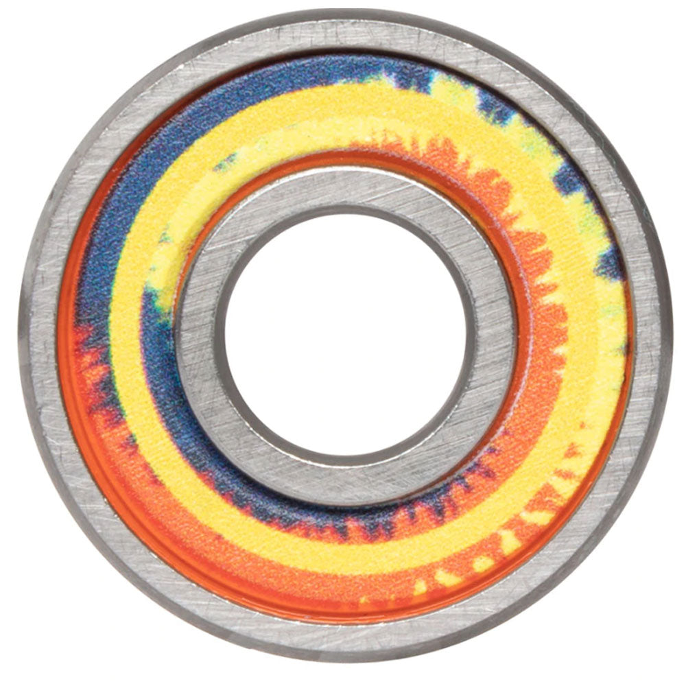 A close-up of a Bronson Speed Co. Bearings Aaron Jaws Homoki Pro G3 metal bearing, showcasing vibrant tie-dye rings in yellow, blue, red, and orange around the inner edge and a hollow center.