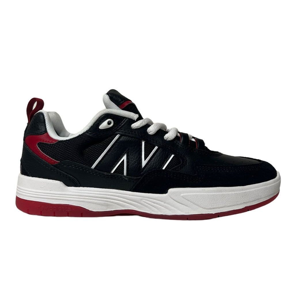 The New Balance NM 808 Tiago Black Red White is a black athletic sneaker with white laces, a white and red sole, red accents on the heel and tongue, and crisp white detail lines on the sides.