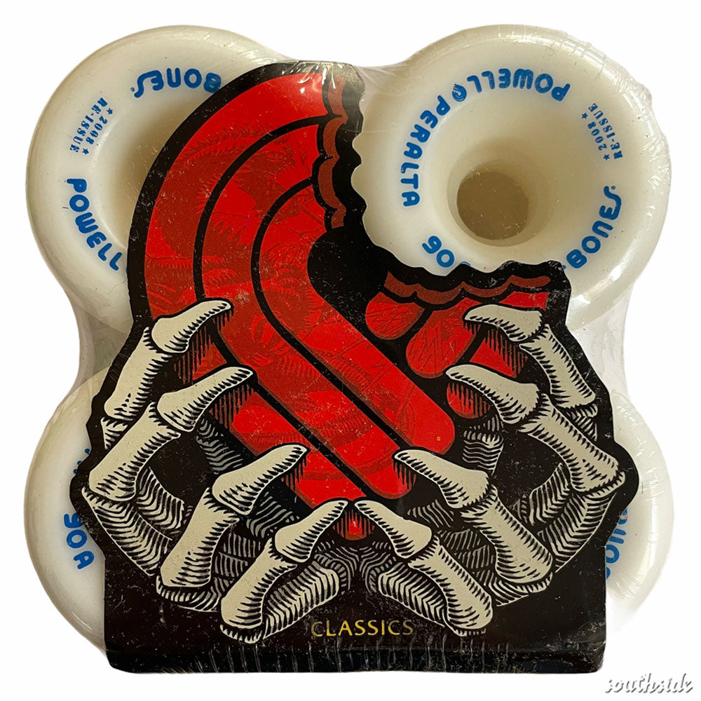 Four white Powell Peralta Rat Bones 60mm 90A wheels with blue text are packaged together, partly covered by a red, stylized S held by a skeletal hand. "CLASSICS" appears at the bottom, evoking the iconic Rat Bones design.