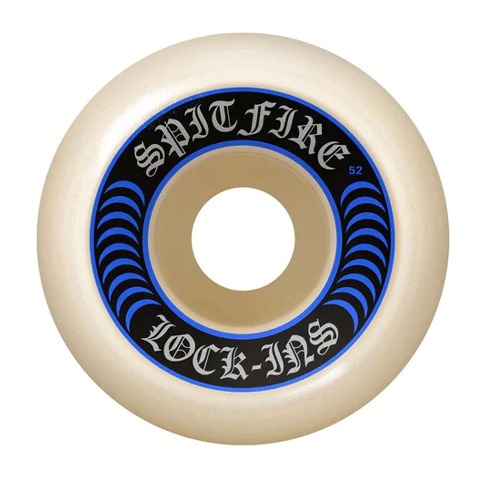 The Spitfire Wheels F4 Lock In 52mm99A is a white skateboard wheel with a black and blue circular design. "SPITFIRE LOCK-INS" appears in Gothic letters, and size/specs are marked on the outer ring for style and performance.