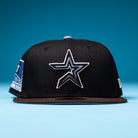 Introducing The Magician Houston Astros New Era Hat 5950 Fitted: a black flat-brimmed fitted hat showcasing a silver-outlined star Houston Astros logo on the front, blue side accents, and the signature New Era logo—all set against a solid blue background.