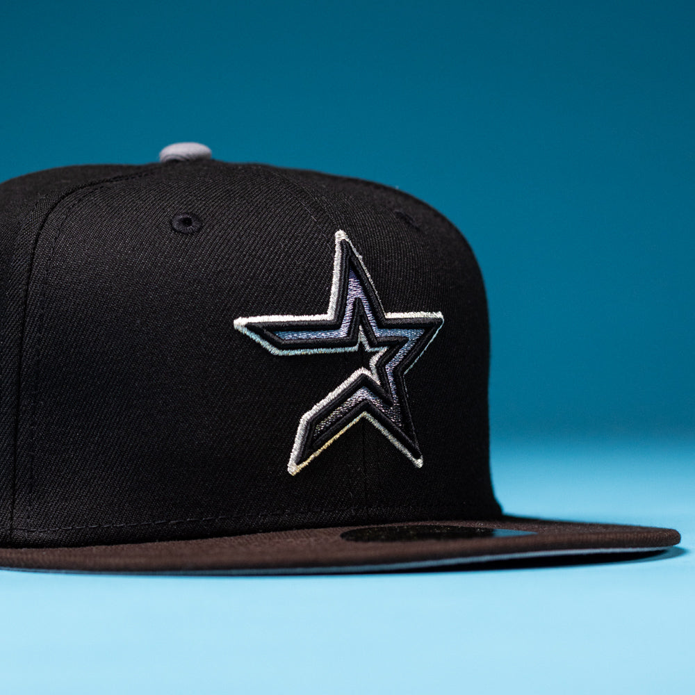 The Magician Houston Astros New Era Hat 5950 Fitted is a black snapback featuring a silver and white outlined star logo inspired by the Houston Astros on the front, displayed on a blue surface with a blue background—perfect for Whatafitted collectors.