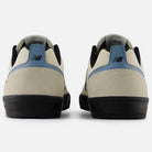 Back view of the 306 SBB Jamie Foy Sea Salt Still Water New Balance Numeric suede skateboarding shoes, featuring beige uppers, black soles, blue heel tab accents, and the signature New Balance logo—ideal for vulcanized skate shoe fans.