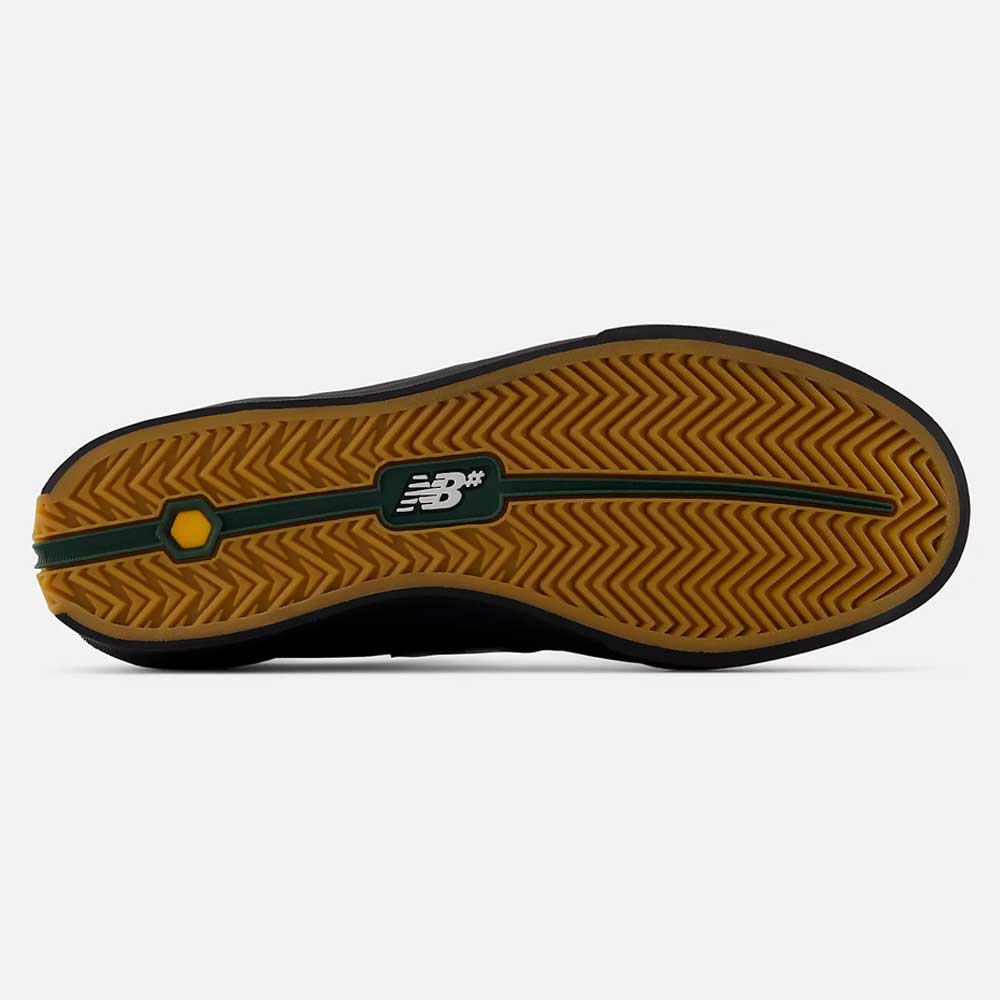 The image shows the gum rubber sole of the New Balance Numeric 340 YRW Black White Suede Skateboarding Shoe, featuring a herringbone tread pattern and the New Balance logo in the center, with a green stripe and yellow accent details. Designed for impact protection, this shoe combines both style and functionality.