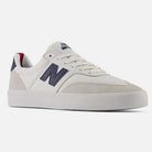 The 340 YRW New Balance Numeric Suede Skateboarding Shoes are white sneakers with a navy blue N logo on the side, suede accents, white laces, and a reinforced toe cap for enhanced durability. Designed with a rubber sole, these shoes are displayed at an angle on a plain white background.