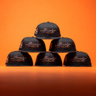 Six BLVCK STAR Houston Astros New Era Hat 5950 Fitted caps are arranged in a pyramid on an orange background.