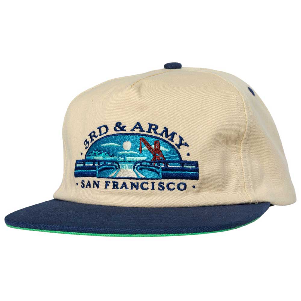 The 3rd and Army Natural Navy Real Skateboards Hat Adjustable is a beige and navy blue hat featuring an embroidered design with the words “3RD & ARMY SAN FRANCISCO,” a bridge, and a cityscape under a full moon—perfect for fans of 3rd and Army or anyone looking for an authentic Real Skateboards accessory.