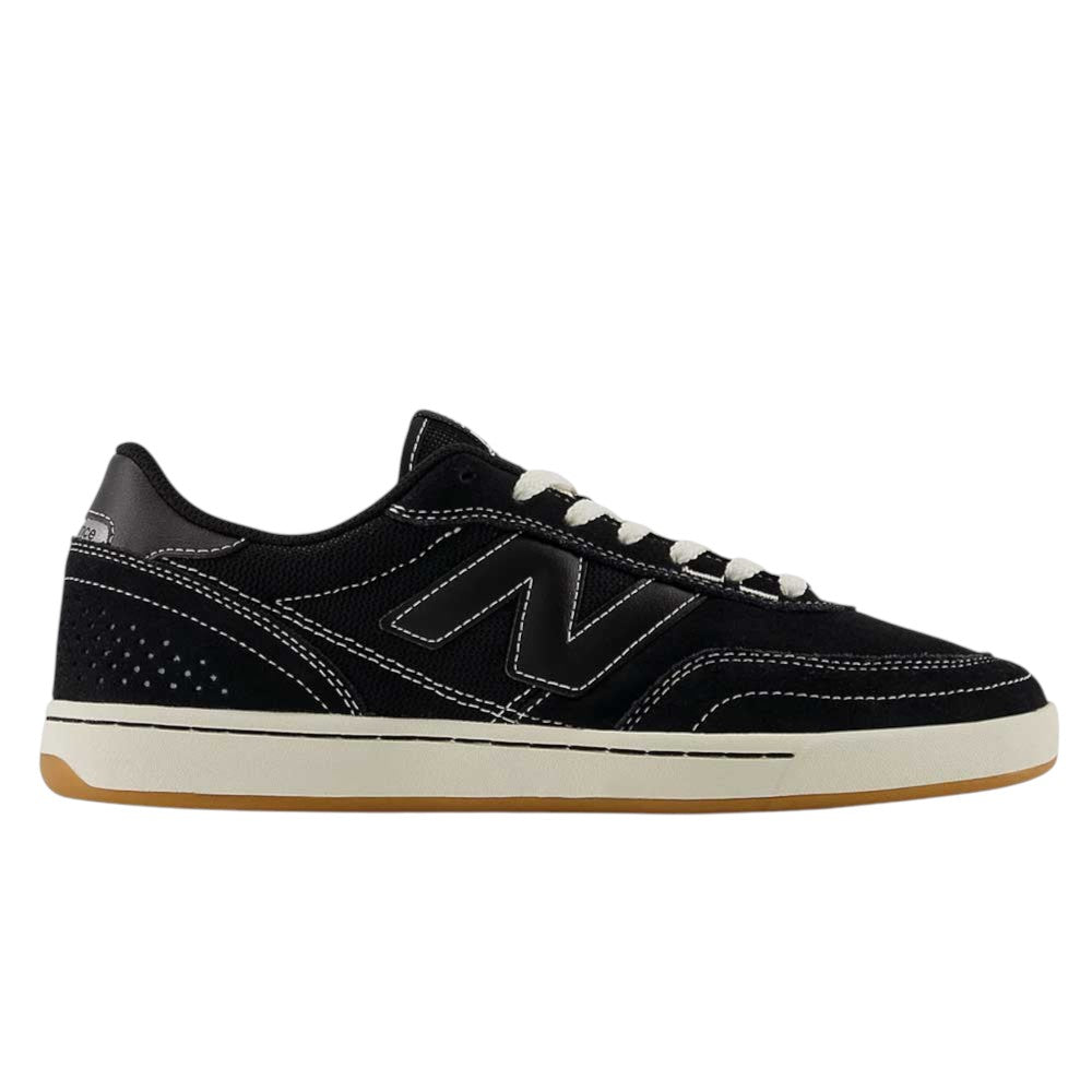 The 440 BCO Black White New Balance Numeric Suede Skateboarding Shoe is a black low-top sneaker featuring white stitching, white laces, and a beige sole. It showcases a prominent N logo on the side, subtle perforated detailing near the heel, and is equipped with a durable ABZORB midsole for enhanced comfort—making it an excellent choice for skateboarding or everyday wear.