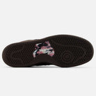 The image shows the sole of the Chocolate Brown 480 CHC New Balance Numeric Suede Skateboarding Shoes, featuring a black rubber tread pattern with white, pink, and black paint-splatter accents at the midfoot.