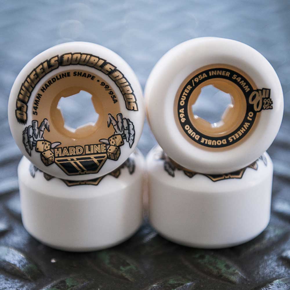 Close-up of four 53mm Double Duro Gum Hardline 101a 95a OJ Wheels: two upright display the black and gold OJ Wheels branding, while two lie flat, all in white.