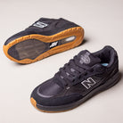 A pair of Black 933 NAP New Balance Numeric Suede Skateboarding Shoes is displayed on a light background—one upright showing the side and laces, the other on its side highlighting the gum sole and tread pattern.