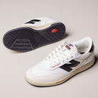 A pair of White Black 440 NO2 New Balance Numeric Suede Skateboarding Shoes with durable ABZORB midsoles; one shoe stands upright showing side and top, the other lays on its side highlighting the sole and logo on a light surface.
