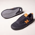 A pair of White Black 306 BON New Balance Numeric suede skateboarding shoes. One vulcanized shoe stands upright, displaying side and top views; the other lies on its side, highlighting the textured grip sole.