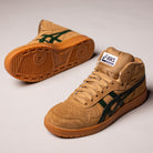 The Japan Pro MT Asics Walnut Forest Night 1201B033200 suede skateboarding shoes feature a tan high-top design with green side stripes, beige laces, gum soles, and Asics branding on the tongue, shown on a light background.