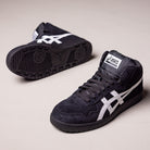 A pair of Japan Pro MT Asics Black Bright White 1201B003003 suede skateboarding shoes—black high-tops with white side stripes—one upright, one on its side showing the sole, on a plain light background.
