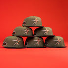Five The Original Olive Black CC Astros New Era Hat 5950 Fitted caps, with orange star logos and black bills, form a pyramid against a red background. Each features a black patch on the left side.