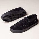 The Skate Loafer Vans VN000VA6BKA1 Black Black Suede Skateboarding Shoes feature thick rubber soles for extra grip and impact protection; one shoe is shown on its side revealing the textured sole, while the other stands upright on a light background.