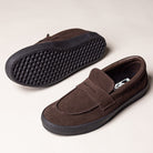 The Skate Loafer Vans VN000VA6Y491 Brown Black Suede Skateboarding Shoes feature black rubber soles for great grip. One shoe is upright showing the top and side, while the other displays the textured sole pattern.