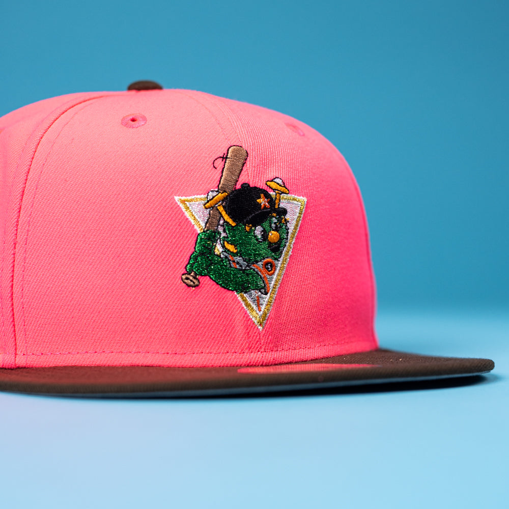 The Pink Comet WS22 Houston Astros 5950 Fitted by New Era features a bright pink crown, brown brim, and an embroidered cartoon character with a bat in green on a blue and triangular patch.