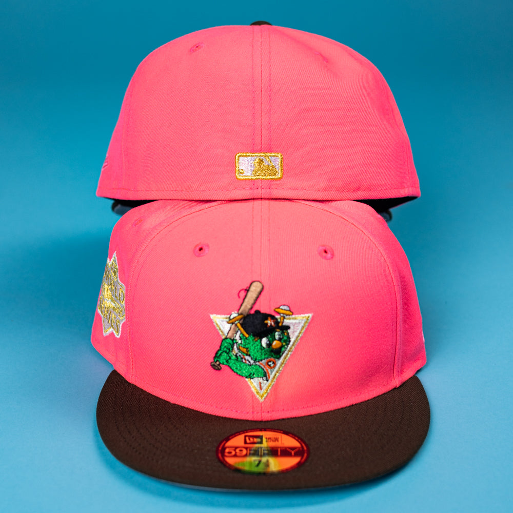 Two Pink Comet WS22 Houston Astros New Era 5950 Fitted hats with black brims are stacked. The front hat features a green cartoon alligator with a bat inside a white triangle. Both have gold patches and are set against a blue background.