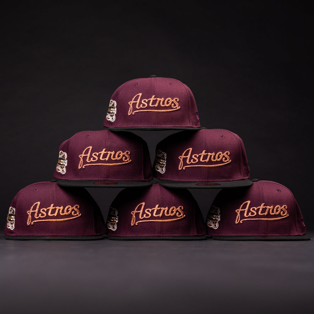 Six 05 Debut Maroon Black Houston Astros New Era Hat 5950 Fitted caps are stacked in a striking pyramid against a dark background, showcasing their elegant gold embroidery.