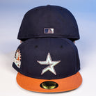 Two The Feast Navy Rust Houston Astros New Era Hat 5950 Fitted caps are stacked, showing the star logo and an orange brim on the front hat, with a Statue of Liberty patch on the side and a small MLB logo on the back cap.