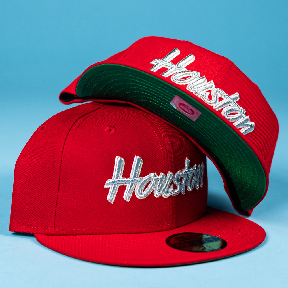 Two Cougar Scarlet Houston Cougars New Era Hat 5950 Fitted caps: one upright, one tilted to show the green underside. Both feature bold red fabric and "Houston" in white script, set against a vivid blue background—a true classic.