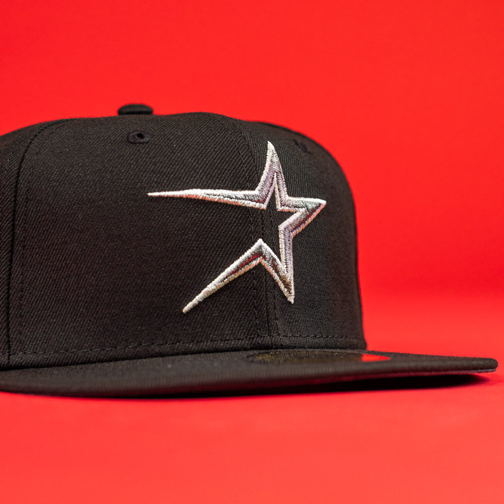 The Shootah Black Silver New Era Hat 5950 Fitted features a silver embroidered star logo on the front and is shown against a bright red background.