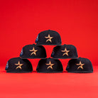 Six 6am in Texas Navy Red White New Era Hat 5950 Fitted baseball caps with gold-outlined star logos are stacked pyramid-style against a red background. Blue and white side patches reflect the signature Navy Red White New Era look.