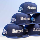 A stack of Fat Elvis OE ASG Dark Blue New Era Hat 5950 Fitted hats, featuring bold white “Astros” on the front and an “All Star Game” patch on the side, is neatly arranged against a light blue background.