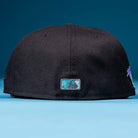 The Flamingo and Chill Bo Bundy 2022 Houston Astros New Era Hat 5950 Fitted is shown from the back, with a small, rectangular embroidered MLB logo in teal, black, and white above the brim against a blue background.