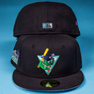 Two black Flamingo and Chill Bo Bundy 2022 Houston Astros New Era 5950 Fitted caps are on a blue background; the front cap has a colorful cartoon character with a bat and triangle, while the back shows a small rectangular patch.
