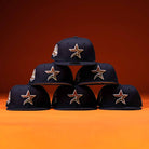 Six Highclass 45th Houston Astros New Era Hat 5950 Fitted hats with gold star logos are stacked in a pyramid against an orange background, showcasing their iconic style.