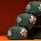 Three stacked El Jager Mountain Orange New Era Hat 5950 Fitted caps are displayed on an orange background, each featuring a Houston patch and a silver Texas outline with an orange star—an eye-catching New Era collection.