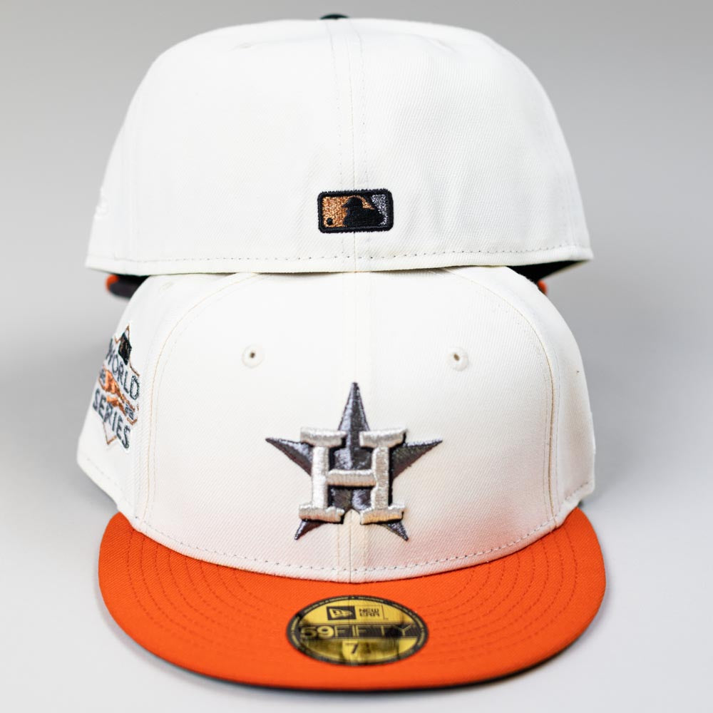 Two Orange Soda New Era WS22 Houston Astros 5950 Fitted hats are stacked, each with an orange brim and metallic Astros logo, an MLB logo on the back of the top cap, and a World Series patch on the side of the bottom cap.