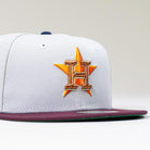 The Shibuya Lights New Era Silver Japan Houston Astros 5950 Fitted Hat features an embroidered gold H over an orange star, a sleek nod to the Astros—complete with a gray crown and maroon brim.