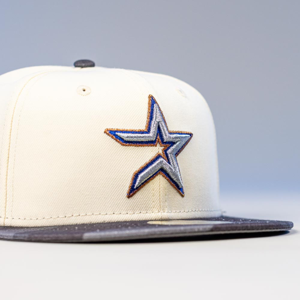 The Dark:30 New Era Chrome Black Camo Houston Astros 5950 Fitted Hat features a cream crown, black brim, and an embroidered blue and silver star with a gold outline on the front, all set against a plain, neutral background.
