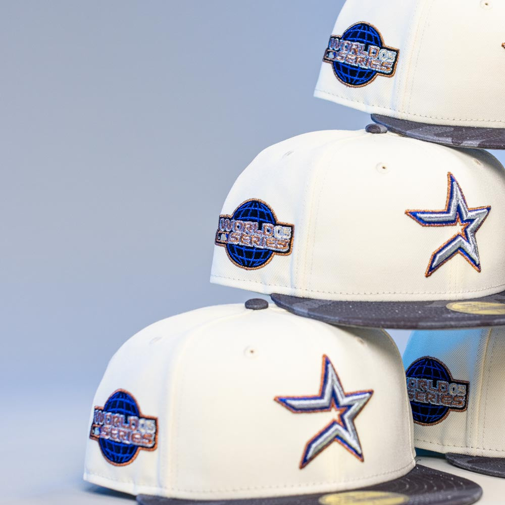 A stack of Dark:30 New Era Chrome Black Camo Houston Astros 5950 Fitted hats is arranged in two uneven piles against a plain background.