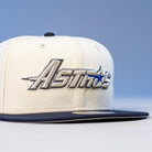 The International Flea Bo Bundy 5950 Fitted New Era Houston Astros Hat is white and navy, featuring "Astros" embroidered in silver and blue on the front with a blue star in the design.