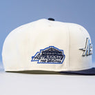 The International Flea Bo Bundy New Era Houston Astros 5950 Fitted Hat is white with blue trim, features an embroidered building and "Astrodome The Original" text on the side, set against a soft, blurred blue background celebrating Astros heritage.