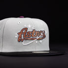 The Pixie Dust New 2000 Houston Astros New Era Hat 5950 Fitted is grey with a black brim, featuring an orange and brown Astros logo with a white orbit and stars embroidered on the front—a must-have for fans.