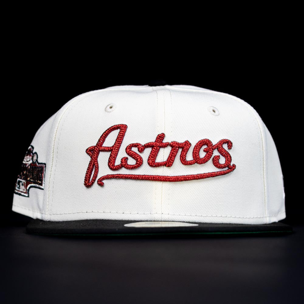 The Red Soda New Era HOF Red Black Chrome Houston Astros 5950 Fitted Hat features "Astros" in red script on the front, with a black brim, shown against a black background.
